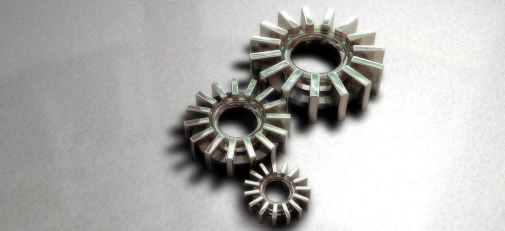 Trois engrenages métalliques futuristes de tailles différentes sur fond gris, illustrant un concept technologique ou mécanique