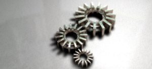 Trois engrenages métalliques futuristes de tailles différentes sur fond gris, illustrant un concept technologique ou mécanique