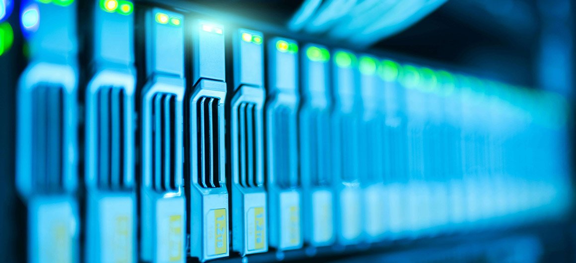 Gros plan sur une rangée de serveurs informatiques éclairés en bleu avec des voyants lumineux verts.